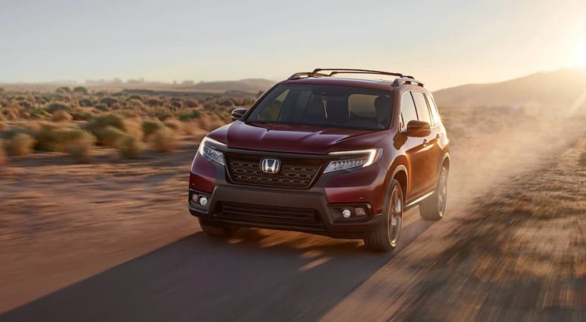 A red 2020 Honda Passport Elite is shown driving through a desert.