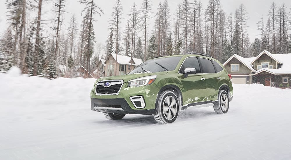 A green 2019 Subaru Forester is shown from the front at an angle while it drives through snow.
