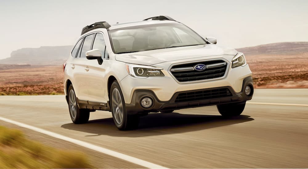 A white 2019 Subaru Outback is shown from the front while it drives down the highway.