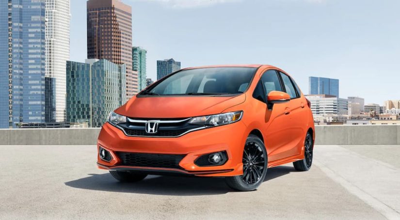 An orange 2020 Honda Fit is shown from the front while parked on a parking garage.