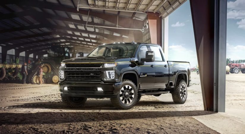 A black 2022 Chevy Silverado 2500HD Carhartt Edition is shown from the front at an angle while parked in a barn.