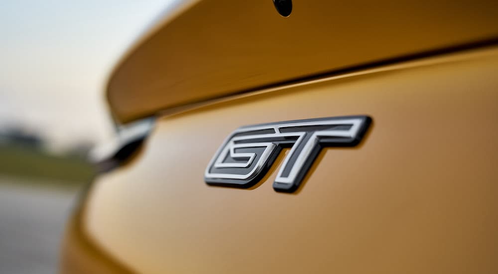 A closeup of the rear badge of a yellow 2022 Mustang Mach-E GT is shown.