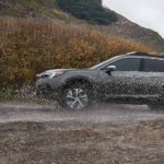 A grey 2021 Subaru Outback is shown from the side while it drives through a puddle after leaving a used Subaru dealer.