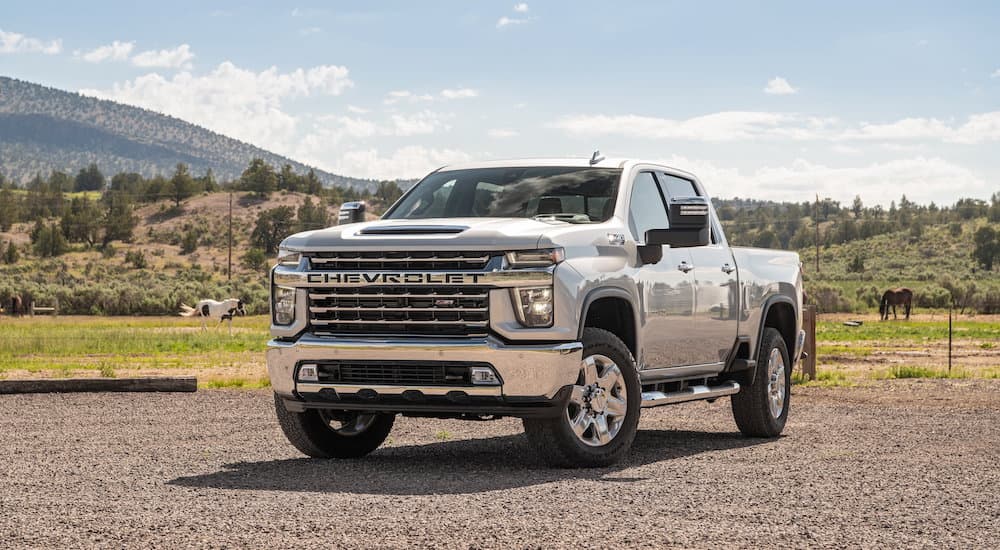 A silver 2022 Chevy Silverado 2500HD is shown from the front at an angle while parked in field during a 2022 Chevy Silverado 2500 HD vs 2022 Ford F-250 comparison.