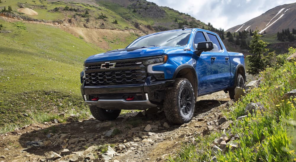 A blue 2022 Chevy Silverado ZR2 is shown from the front at an angle while driving down an off-road trail.