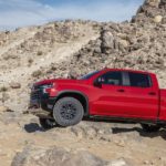 A red 2022 Chevy Silverado ZR2 is shown from the side while crawling over rocks.