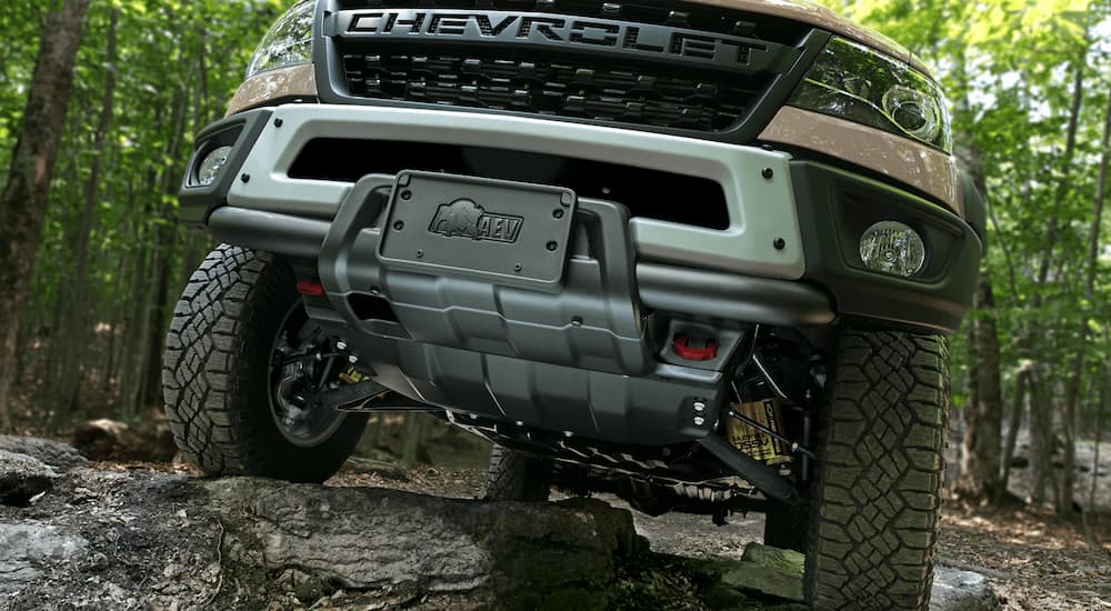 A close up of the grille of a 2022 Chevy Colorado ZR2 Bison is shown driving up a rocky trail.