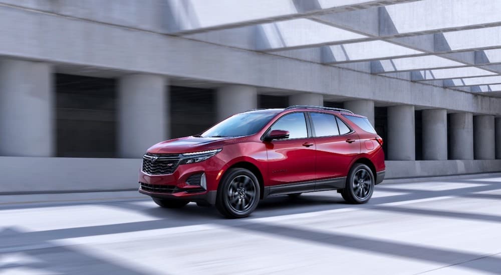 A red 2022 Chevy Equinox RS is shown from the side while it drives down a covered highway.