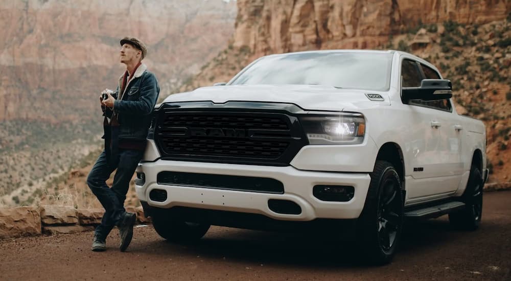 A man is shown leaning up against a white 2022 Ram 1500.
