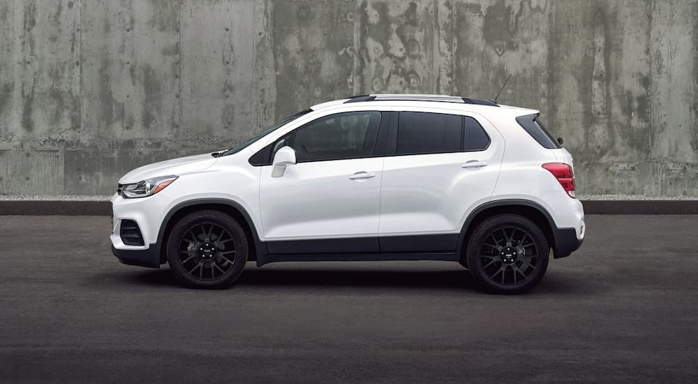 A white 2022 Chevy Trax is shown from the side parked in front of a concrete wall.