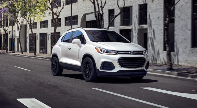 A white 2022 Chevy Trax is shown from the front driving through a city.