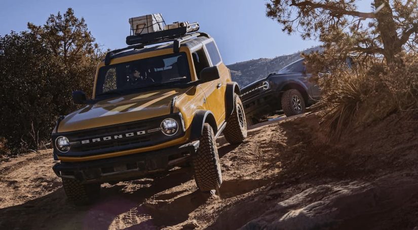An orange 2022 Ford Bronco is shown off-roading on a rocky trail.