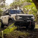 A tan 2022 Ford Bronco Everglades is shown parked on a muddy trail.