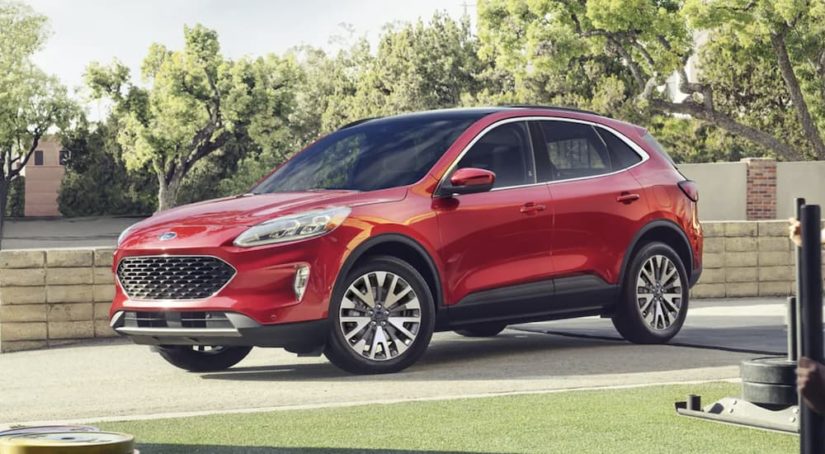 A red 2022 Ford Escape is shown from the side parked in a driveway during a 2022 Ford Escape vs 2022 Toyota RAV4 comparison.