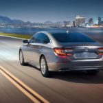 A silver 2022 Honda Accord LX is shown from the rear driving during a 2022 Honda Accord vs 2022 Kia K5 comparison.