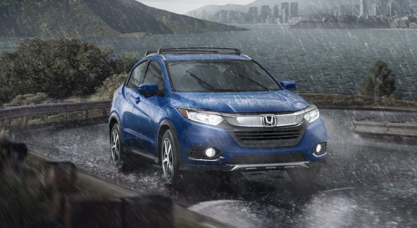 A blue 2022 Honda HR-V EX is shown from the front driving on an open road in the pouring rain.
