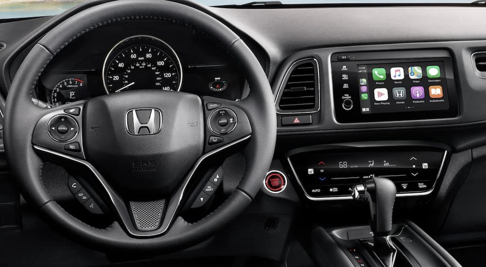 The black interior of a 2022 Honda HR-V EX-L shows the steering wheel and infotainment screen.