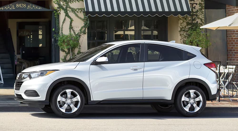 A white 2022 Honda HR-V LX is shown from the side parked in front of a store.