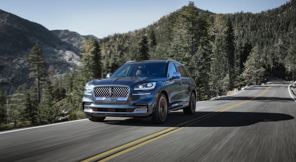 A grey 2022 Lincoln Aviator is shown from the front driving on a mountain highway.