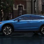 A blue 2022 Subaru Crosstrek Limited is shown from the side driving through a city.