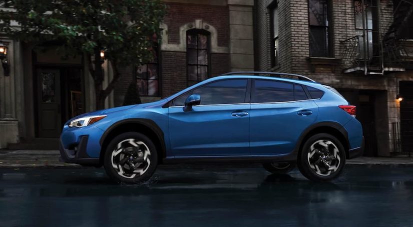 A blue 2022 Subaru Crosstrek Limited is shown from the side driving through a city.