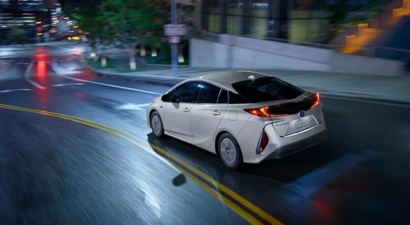 A silver 2022 Toyota Prius Prime is shown from the rear driving on a city street.
