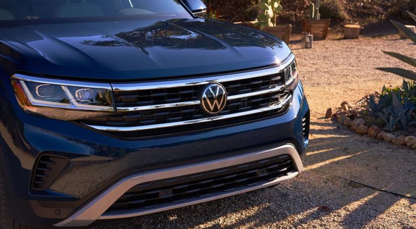 A close up of the hood of a blue 2022 Volkswagen Atlas is shown in a driveway.