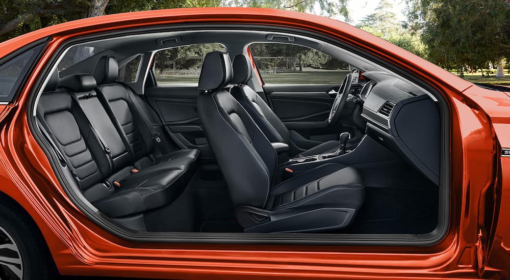 The black interior of an orange 2022 Volkswagen Jetta is shown from the side during a 2022 Volkswagen Jetta vs the 2022 Toyota Corolla comparison.