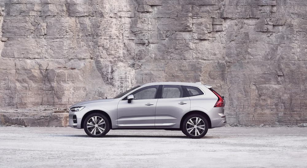 A silver 2022 Volvo XC60 is shown from the side in front of a quarry wall.