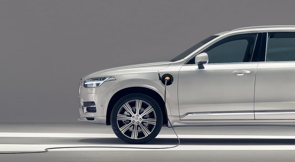 A silver 2022 Volvo XC90 is shown from the side while charging at an EV station.