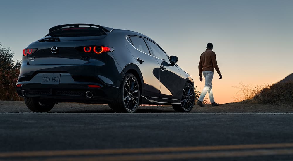 A black 2022 Mazda 3 Turbo is shown from the rear at dusk.