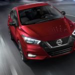 A popular certified pre-owned vehicle, a red 2020 Nissan Versa, is shown driving on a highway.