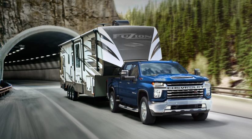 A blue 2022 Chevy Silverado 2500HD is shown from the front while towing a large camper during a 2022 Chevy Silverado 2500 HD vs 2022 Ram 2500 comparison.