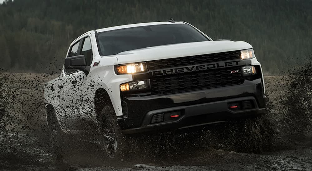 A white 2022 Chevy Silverado 1500 is shown off-roading after leaving a Chevy dealer.