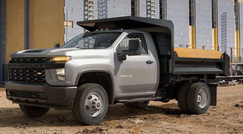 A silver 2022 Chevy Silverado 3500HD Chassis Cab is shown parked at a construction site.
