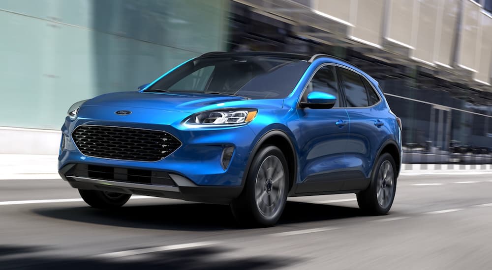 A blue 2022 Ford Escape is shown from the front at an angle while it drives down a street.