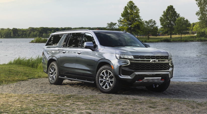 A grey 2022 Chevy Suburban Z71 is shown from the fornt at an angle while it is parked next to a lake during a 2022 Chevy Suburban vs 2022 Ford Expedition comparison.