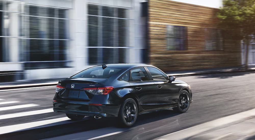A black 2022 Honda Civic Sport is shown from the rear driving through a city after leaving a Honda dealer near you.