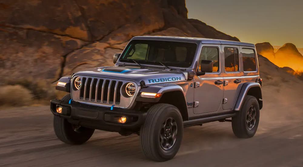 A 2021 Jeep Wrangler Unlimited 4xe is shown from the front at an angle while it drives down a dirt trail.