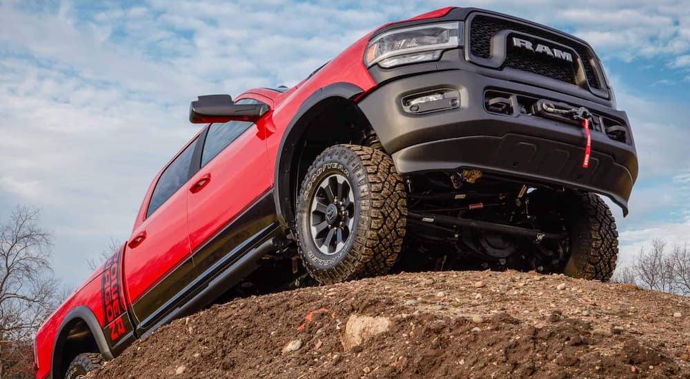A red 2022 Ram 2500 Power Wagon is shown from a low angle while it crawls over a rock.