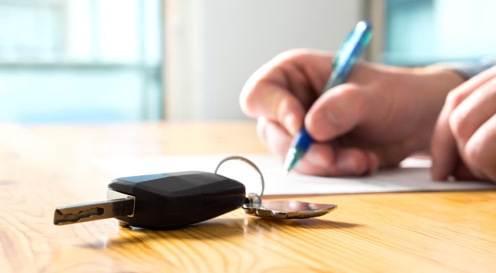 A person is shown preparing paperwork so they can sell their car.