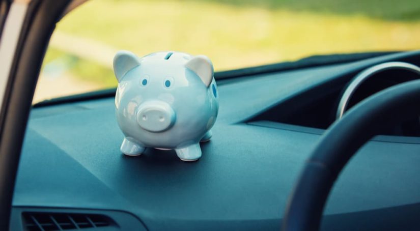 A piggy bank is shown sitting on the dashboard of a vehicle.