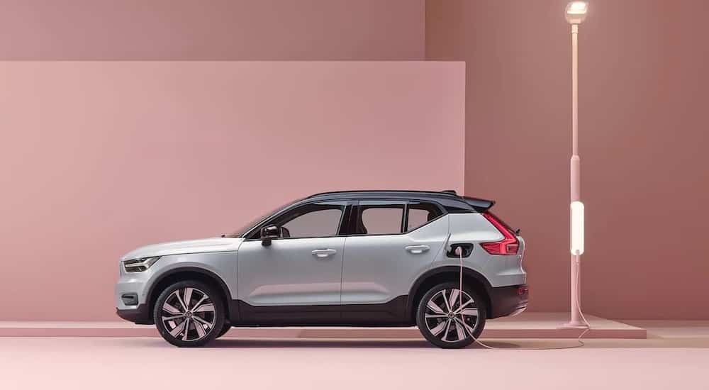 A white 2022 Volvo XC40 Recharge is shown from the side charging on a pink street.