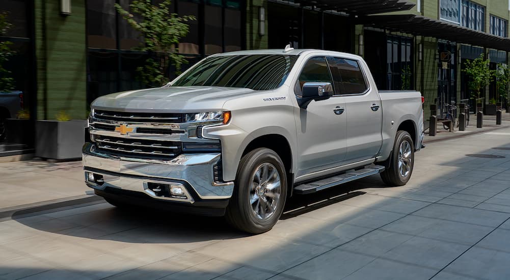 A silver 2019 Chevy Silverado 1500 is shown from the front at an angle on a city street.