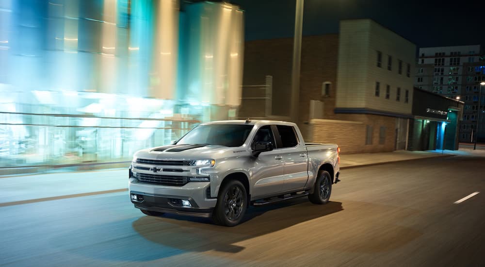 A silver 2020 Chevy Silverado 1500 is shown from the front at an angle on a city street.