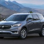 A grey 2021 Buick Enclave Avenir is shown from the front at an angle while parked in a mountainous area.