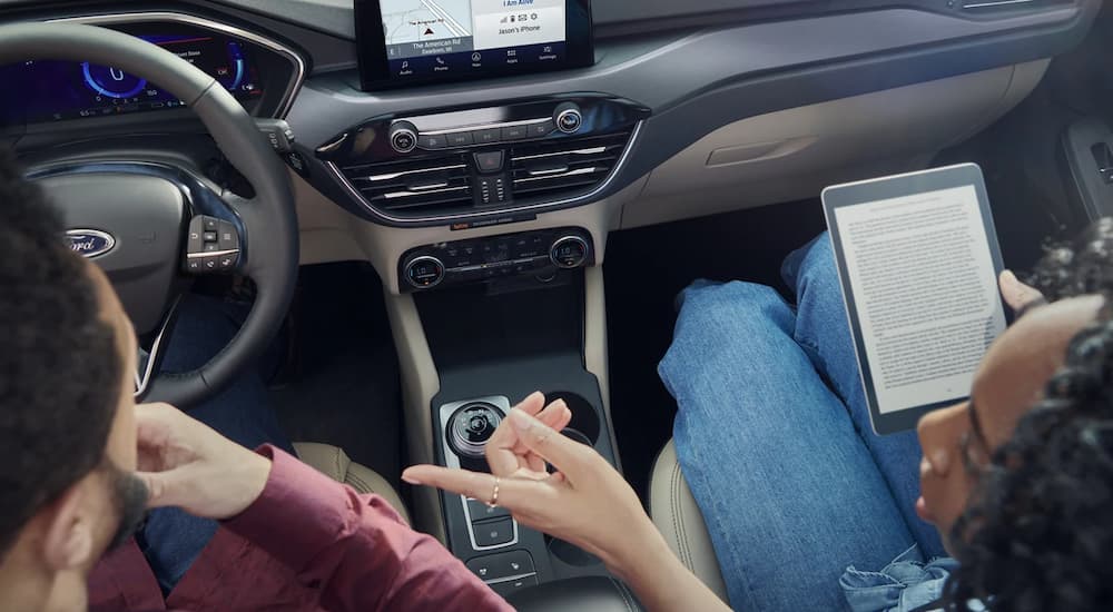 A person is shown reading on a tablet in a 2022 Ford Escape.