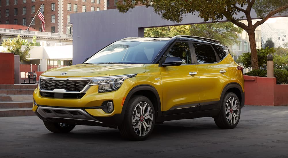 A yellow 2022 Kia Seltos is shown from the front at an angle while parked in an urban area.