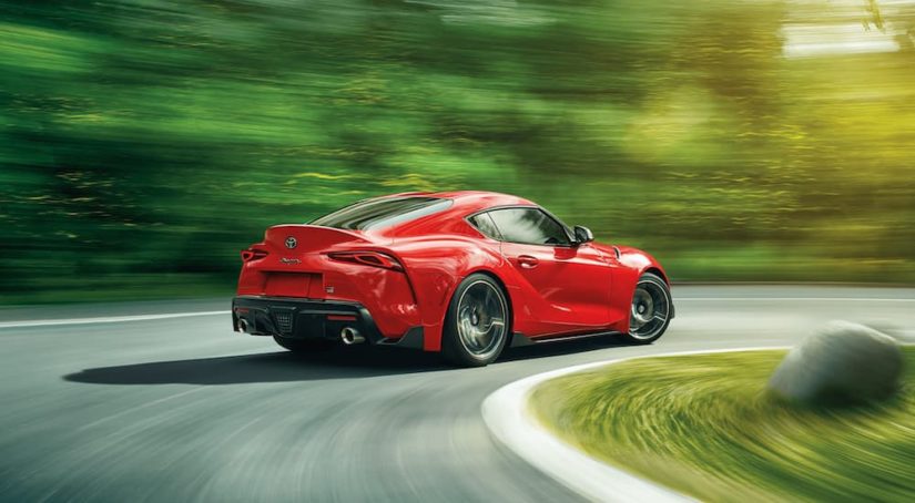 A red 2021 Toyota GR Supra is shown from the rear while rounding a corner after leaving a Toyota Dealership.