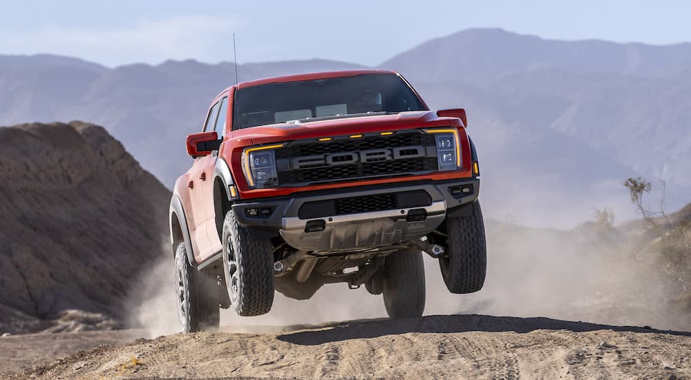 A red 2021 Ford F-150 Raptor is shown from the front while jumping through the air.